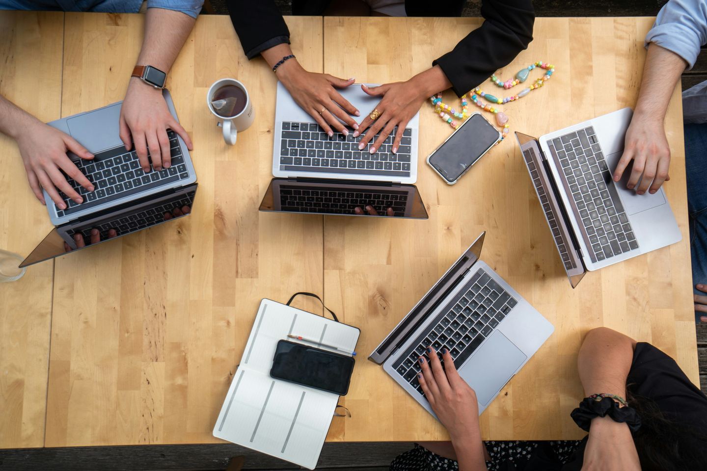 Team working on laptops at a wooden table